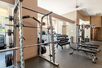 a gym with weights and a row of dumbbells at The Acadia at Metropolitan Park, Arlington